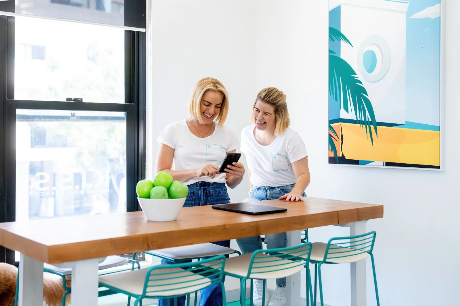 Two K.I.S.S team members laughing over a phone in the Cronulla office